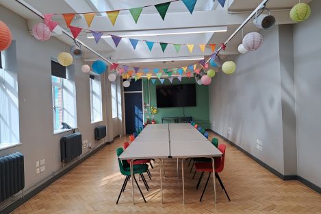 Our long Link Room with colourful bunting on the ceiling and a large table with chairs